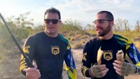 two men in black t-shirts holding a fishing rod